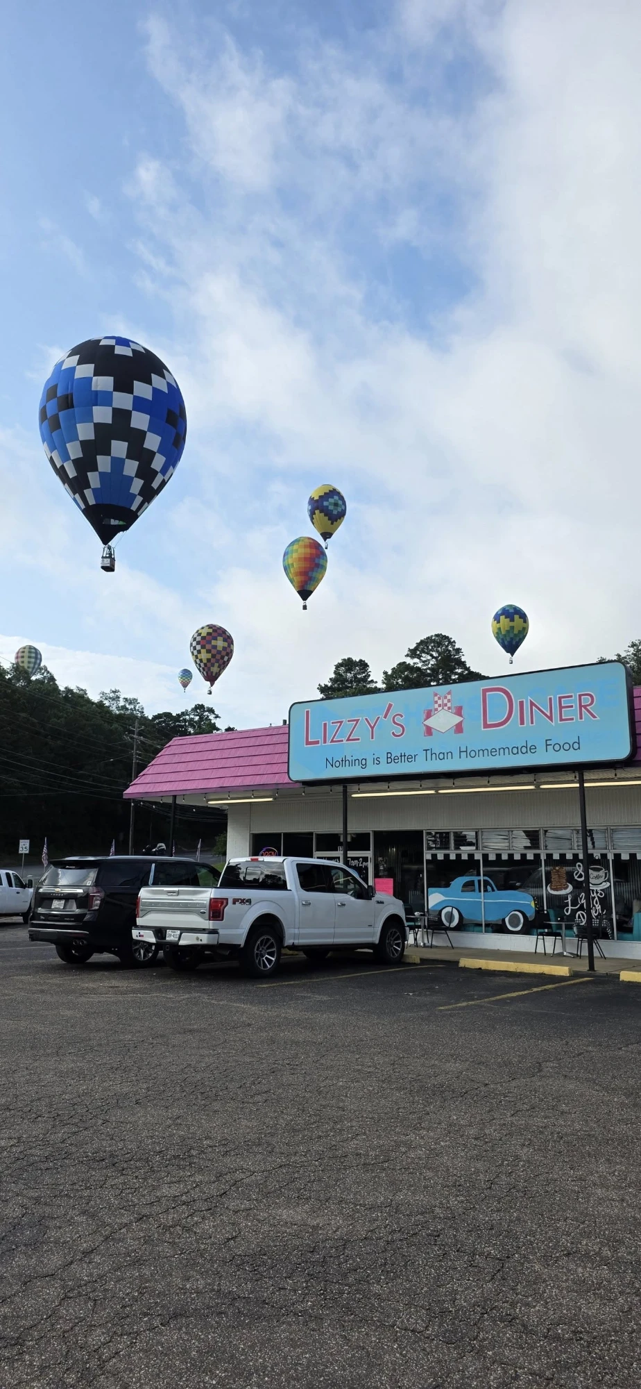 Lizzy's Diner storefront — pink roof and classic sign, with hot-air balloons drifting overhead